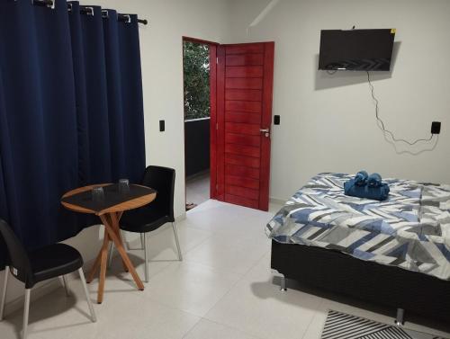 een slaapkamer met een bed en een tafel en een rode deur bij Comfortable studio in an excellent location in Macapá