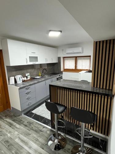 Una cocina con encimera y dos taburetes de bar. en Stan na dan Apartman Durakovic, en Cazin