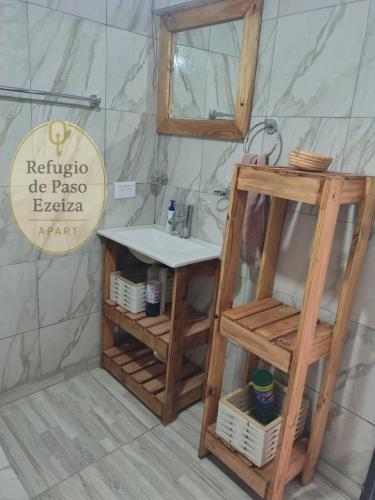 a bathroom with a sink and a wooden shelf at Refugio de Paso Ezeiza in Ezeiza