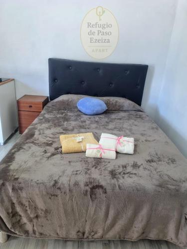 a bed with two towels and a blue pillow on it at Refugio de Paso Ezeiza in Ezeiza