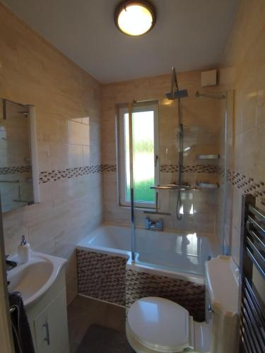 a bathroom with a tub and a toilet and a sink at Lovely place at Stenhouse in Edinburgh