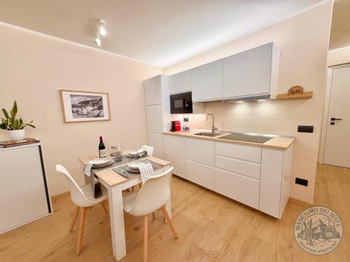 a kitchen with white cabinets and a table and chairs at Madesimo Ski Suite in Madesimo