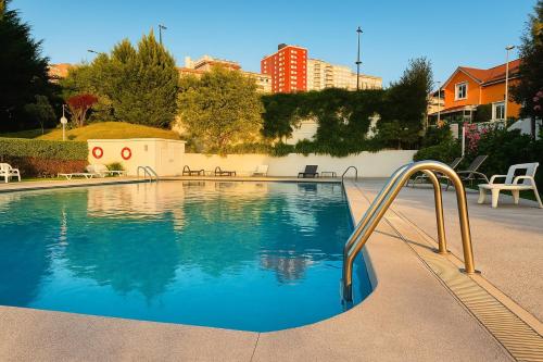 a large swimming pool with a metal handrail in a yard at Apart CityMar 24h Terraza y vistas Ria Vigo in Vigo