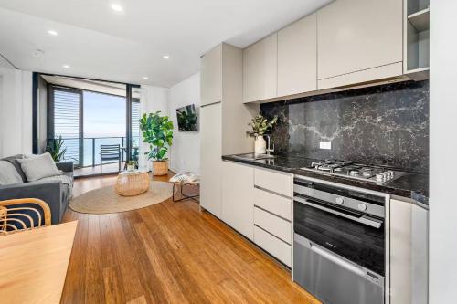 a kitchen with a stove and a living room at 803 - Stylish Retreat - Ocean Views & Parking in Newcastle