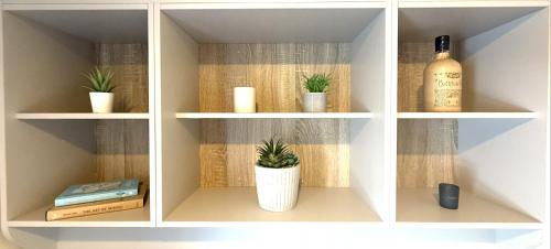 a white book shelf with a bottle of wine and plants at Grand Horizon in Hunmanby