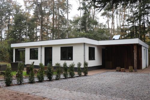 a white house with trees in the background at Natuurhuisje Vechtdal Bungalow met privé sauna zwemmeer en houthaard in Vilsteren