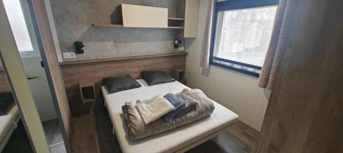 a small bed in a small room with a window at MH310 2 chambres et 2 salles de bain de 40m2 dans camping 4 étoiles in Saint-Julien-en-Born