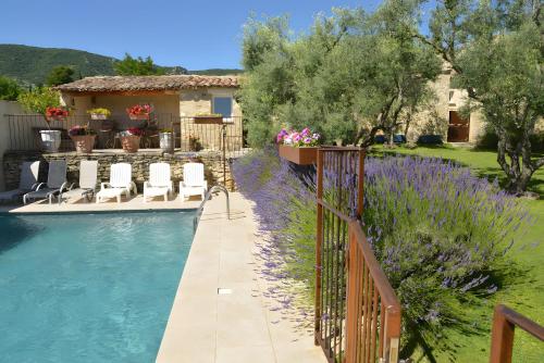 a pool with a fence and purple flowers next to a house at Maison L'oustalette De Mau-bé in Maubec
