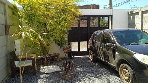 une voiture garée à côté d'un bâtiment avec un arbre dans l'établissement Cazartes antiguo, à Treinta y Tres