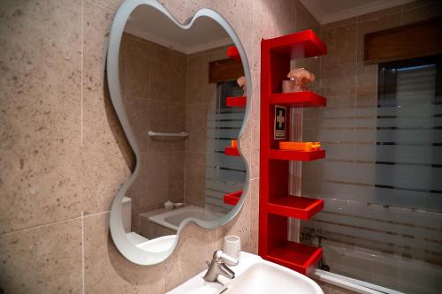 une salle de bain avec une étagère rouge au-dessus d'un lavabo dans l'établissement Vila das Conchas - Enjoy the Seaview Pool with the Beach only steps away, à Sesimbra