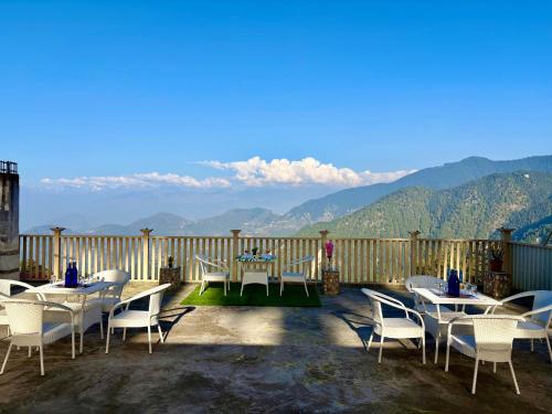 a table and chairs on a deck with a view of mountains at The Zen Villa in Dalhousie
