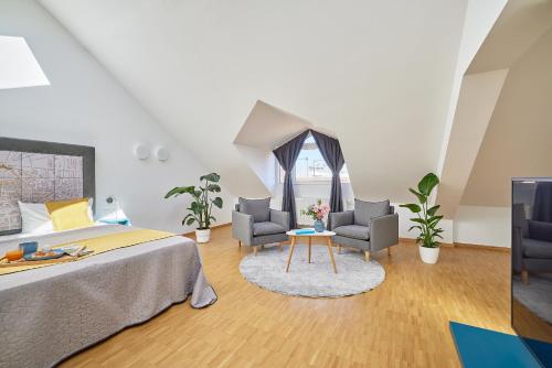 a bedroom with a bed and two chairs and a table at SEEGER Living Premium Downtown in Karlsruhe