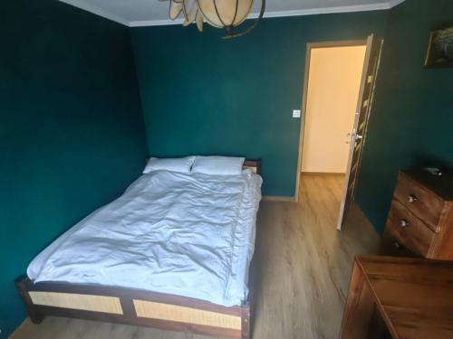 a bed in a room with a green wall at Zielony Balkon in Sanok