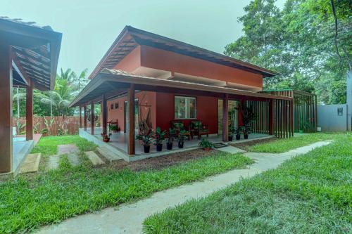una piccola casa rossa con un giardino di fronte di Canto dos Pássaros a Itacaré