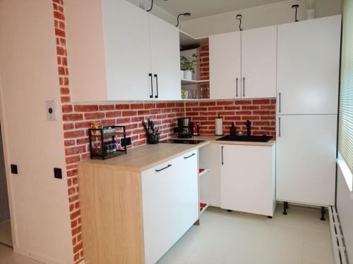 eine Küche mit weißen Schränken und einer Ziegelwand in der Unterkunft Cosy apartment in the heart of Riga in Riga