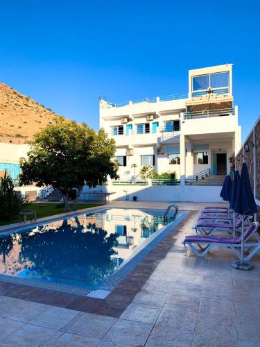 a building with a swimming pool next to a house at Maison D'hôtes Ait Mouli in Bzou