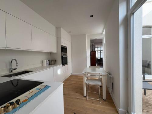 ダンケルクにあるLe Gambetta suiteの白いキャビネットとテーブル付きのキッチンが備わります。