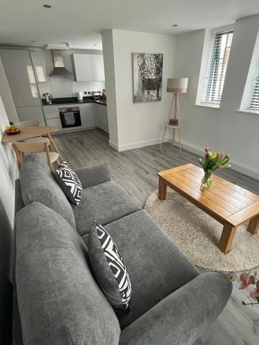 a living room with a gray couch and a table at Modern Flat in central Lichfield & secure parking in Lichfield