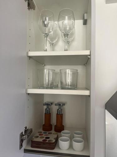 two wine glasses and bowls on shelves in a kitchen at Modern Flat in central Lichfield & secure parking in Lichfield
