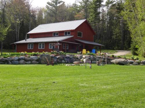 a red barn in front of a green field at Robert Frost Mountain Cabins in Middlebury