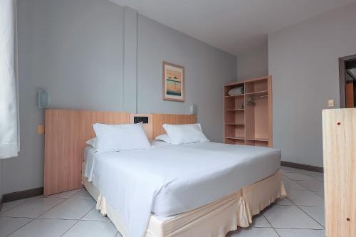 a bedroom with a large bed with white sheets at Hotel Sagres Praia in Balneário Camboriú