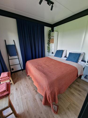 a bedroom with a large red bed with blue pillows at Tiny house Polderzicht in De Veenhoop