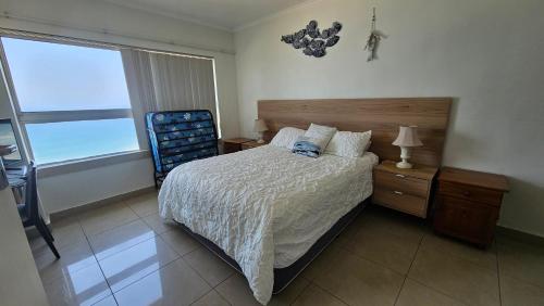 a bedroom with a bed and a chair and a window at Oceanview Holiday Apartments in Amanzimtoti