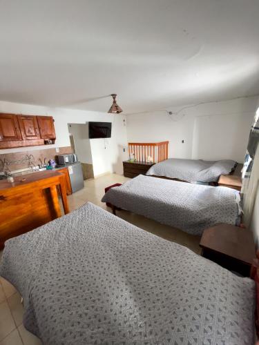a room with three beds and a kitchen with a kitchen at TIlcara Rooms in Tilcara