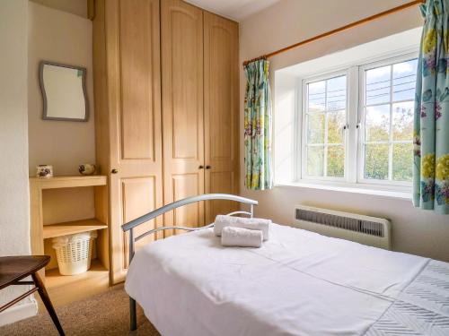 a bedroom with a bed and a window at Poppy Cottage in Charlton Marshall