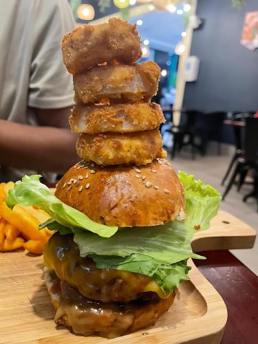 una alta pila de hamburguesas en un plato de madera en Woodland Suites with Airport Shuttle, en Mbabane