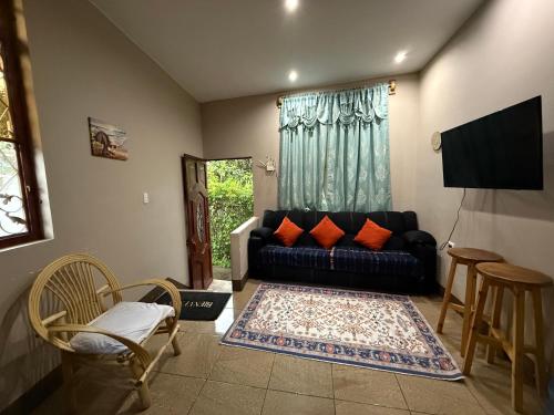 a living room with a black couch and a tv at Apartamentos Jasmin in San Pedro La Laguna