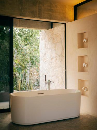 a bathroom with a white tub in front of a window at Casa M in Macario Gomez