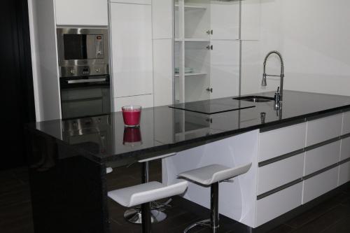 a kitchen with a counter with a sink and stools at Vivenda Paraíso in Candelária