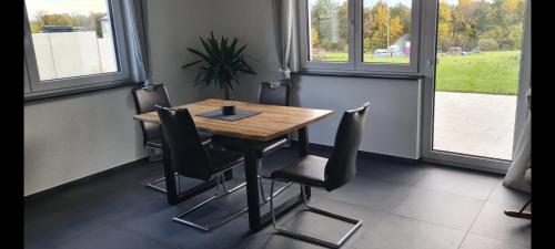 einen Holztisch und Stühle in einem Zimmer mit Fenstern in der Unterkunft M&M AusZeit im Schwabenländle in Winterlingen