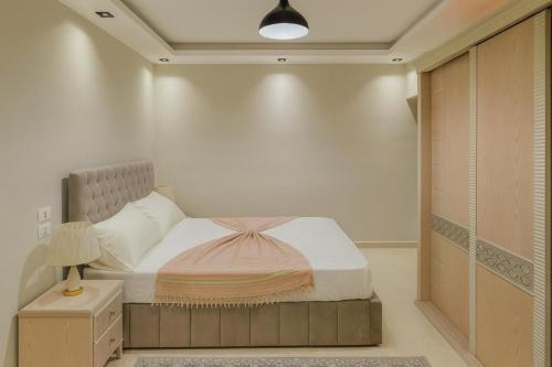 a small bedroom with a bed and a lamp at ALEX HOMES - Gleem Luxury Apartments with Direct Sea View in Alexandria