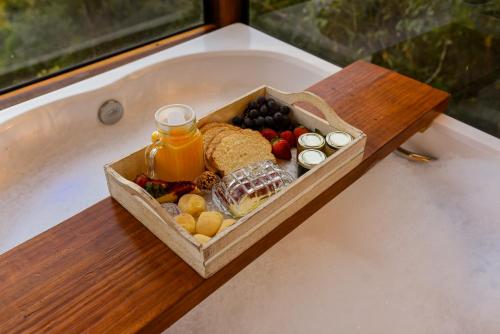 uma bandeja de frutas e suco em uma banheira em Chalé Romântico com Jacuzzi Próximo ao Templo Budista em Três Coroas
