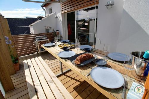 ein Holztisch mit Tellern und Essen auf einem Balkon in der Unterkunft La maison de perros in Perros-Guirec