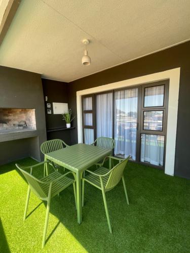 ein Esszimmer mit einem grünen Tisch und Stühlen in der Unterkunft The Oryx Luxury Apartment in Windhoek