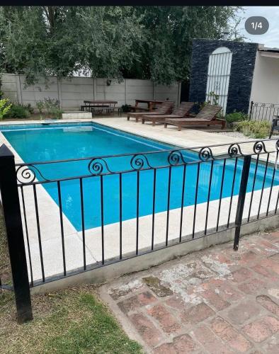 an iron fence with a blue swimming pool at Hotel El Mirador in Chascomús