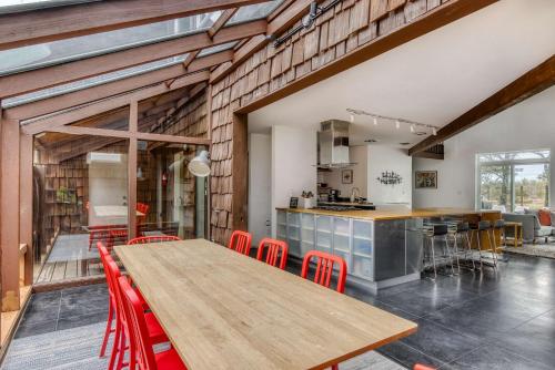 a kitchen and dining room with a wooden table and red chairs at Blue Heron - Modern Chef Kitchen, Hot Tub near Beach in Seaside