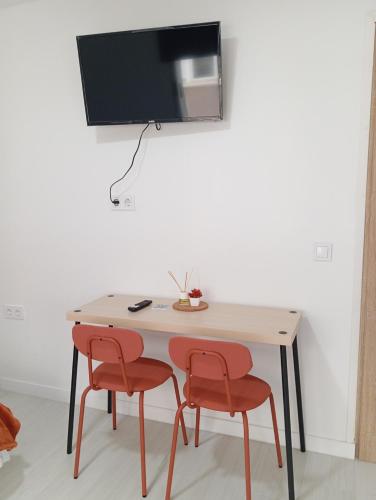 a table with two chairs and a television on a wall at Estudios Diego in Puerto de Sagunto