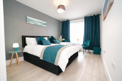 a bedroom with a large bed with blue curtains at Milton Keynes new 5-Bedrooms 14guests Contractor family holiday Free Parking in Milton Keynes