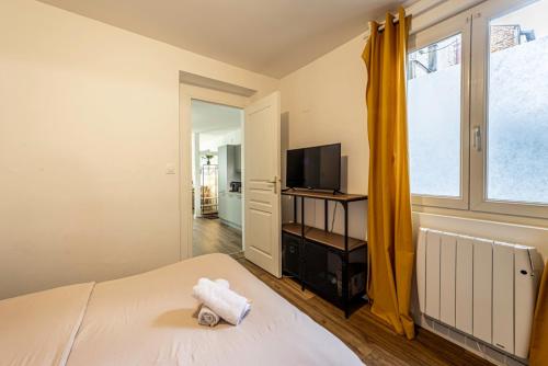 レンヌにあるLe Nid du Graverandのベッドとテレビと窓のある寝室