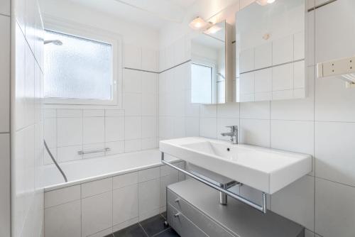 a white bathroom with a sink and a mirror at EXQUIS Design 3-Room Apartment KNOLL I Zurich Lake View I Balcony I Family-Friendly in Männedorf