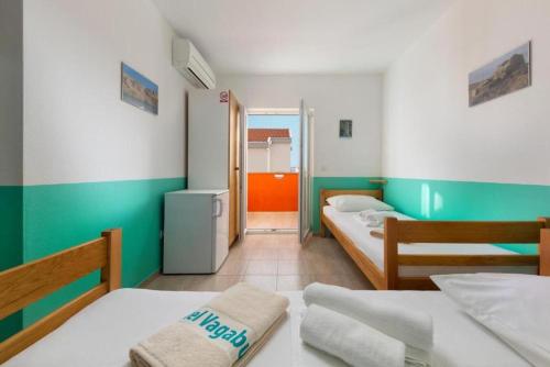 Una pequeña habitación con dos camas y un pasillo. en BUDGET RESORT Vagabundo, en Novalja
