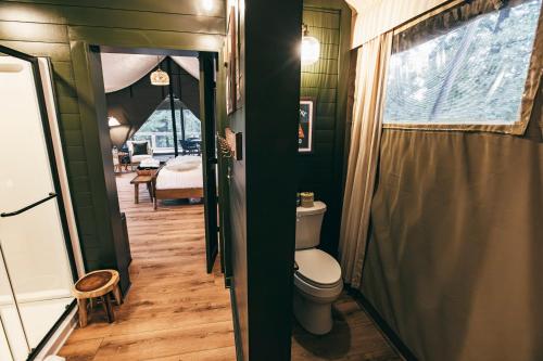 a small bathroom with a toilet and a bedroom at Luxury Glamping Tent - The Perch - Near Tryon Equestrain Center in Mill Spring