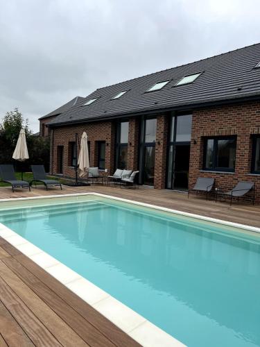 ein Schwimmbad vor einem Gebäude in der Unterkunft Domaine de l'Avesnois in Louvignies-Quesnoy