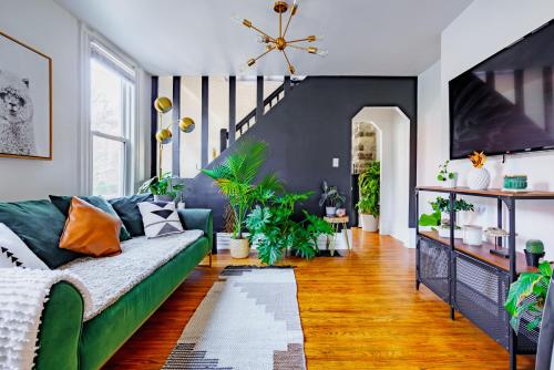 a living room with a green couch and lots of plants at Jungle House Luxury Homes - Columbus Downtown Short North - Steps to Convention Center & Nationwide Arena - Sleeps up to 11 - Free Parking - Over 5,800 Five Stars in Columbus