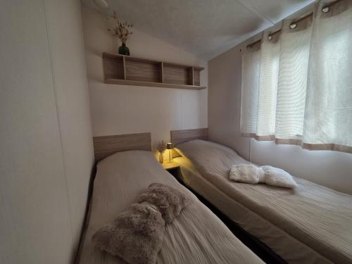 two beds in a small room with a window at Kustchalet in Middelkerke