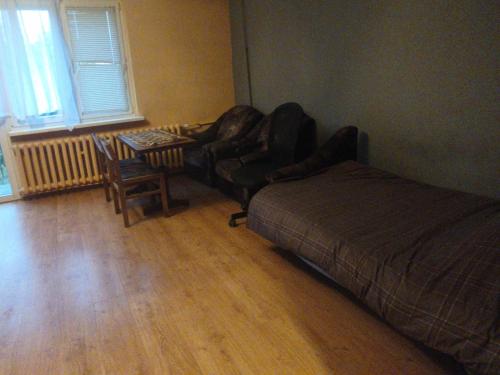 a bedroom with a bed and a chair and a table at Pleasant apartament im center low price in Konin